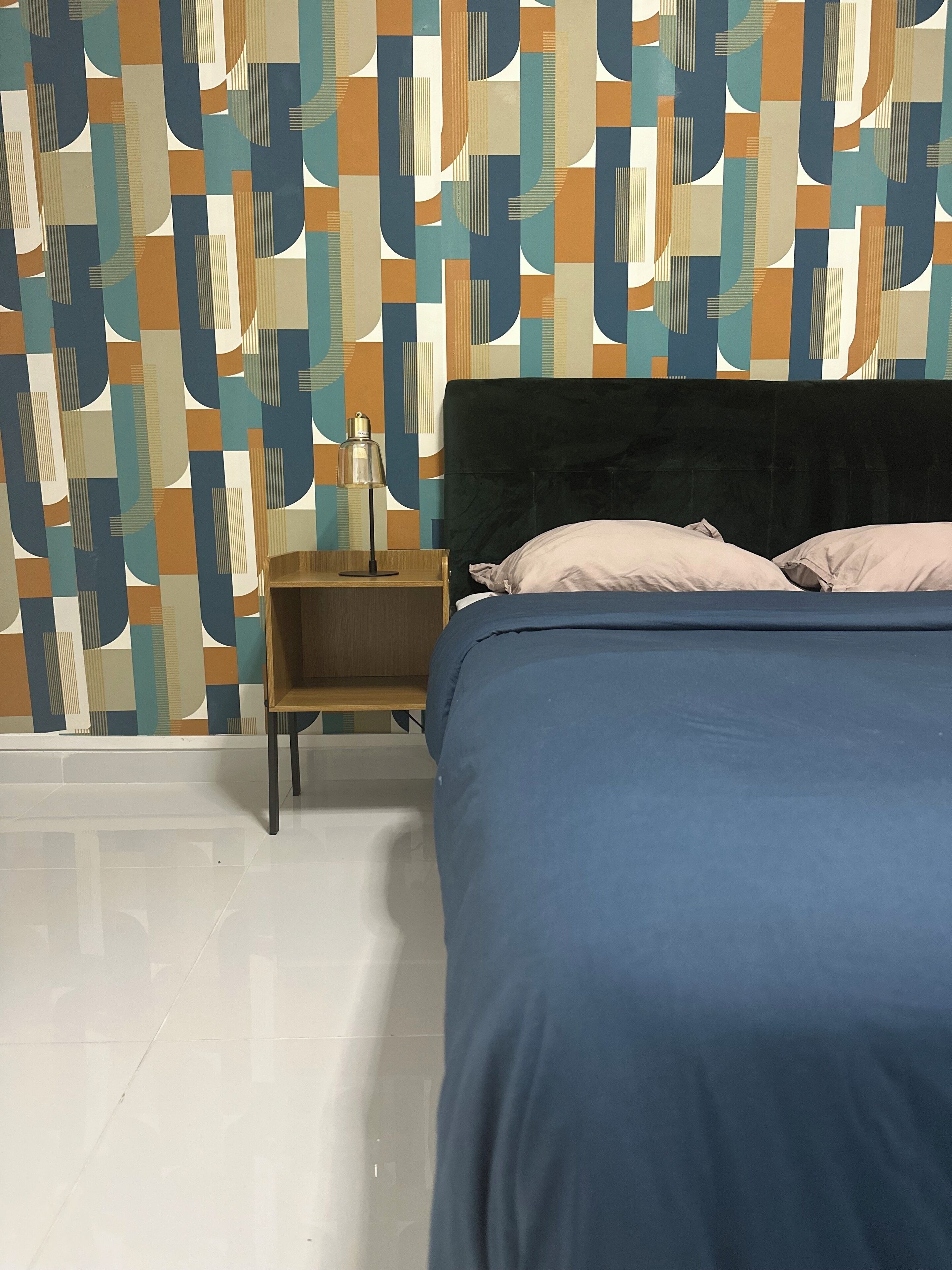 Une chambre à coucher avec un lit, des oreillers, une table de chevet et une lampe.