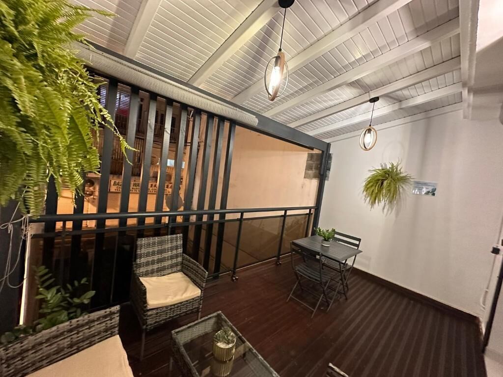Un interior modern amb sòl de fusta, zona de menjador amb taula i cadires, espai de seients amb sofà i una escala amb barana.
