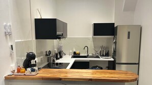 Cocina moderna con una isla central, gabinetes negros, un refrigerador de acero inoxidable y una lámpara en el techo.