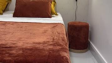 Una camera da letto con un letto, un comodino e una lampada a parete.