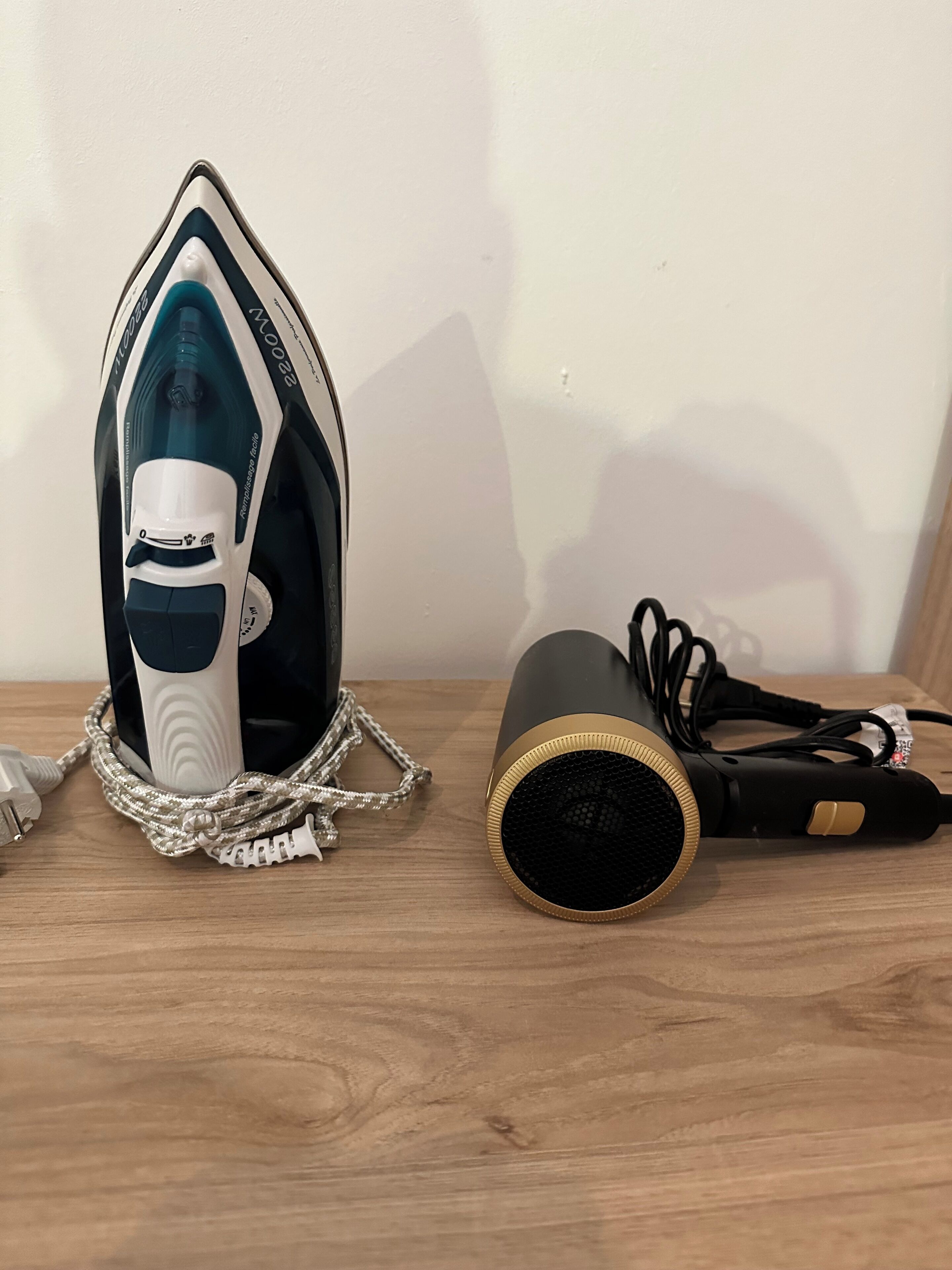 An iron and a hairdryer on a wooden surface.