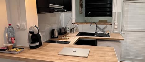 Una cocina moderna con encimera de madera, estufa negra, cafetera y una computadora portátil.