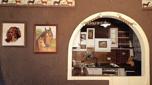 Eine Küche mit einer weißen Rundbogenarchitektur, gerahmten Kunstwerken und einer Kaffeemaschine.