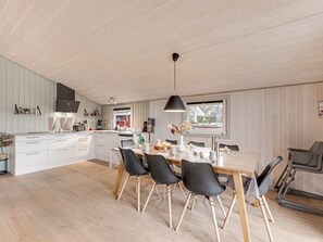 Een moderne keuken met witte kasten, een centraal eiland en een eethoek met een houten tafel en zwarte stoelen.