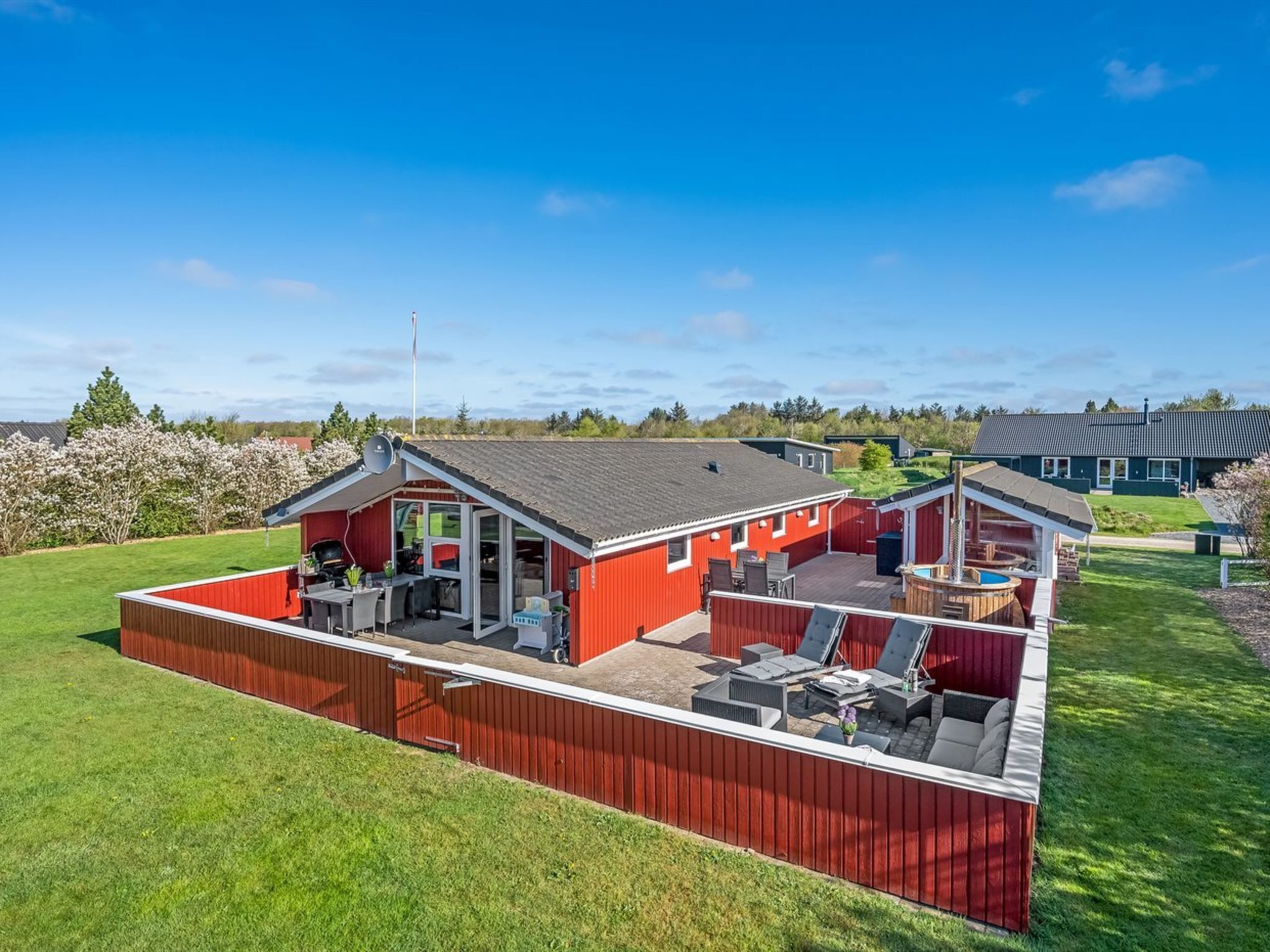 A red-roofed building with a patio area, outdoor seating, and a swimming pool.