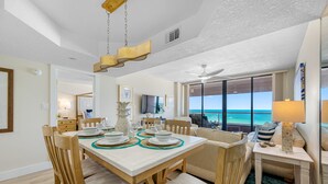 Un comedor con una mesa dispuesta para cuatro, sillas de madera y vista al océano a través de amplios ventanales.