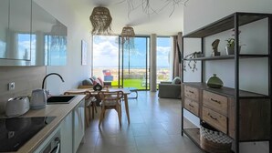 A modern kitchen with a dining area, large windows, and a view of the beach.