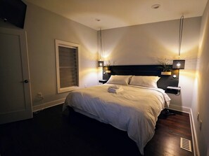 Une chambre à coucher avec un lit, des lampes de chevet, une fenêtre et une porte.