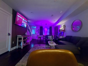 A living room with a sofa, a coffee table, and a TV mounted on the wall.