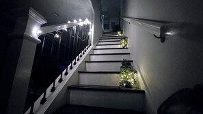 A staircase with white railings and steps, illuminated by overhead lights.