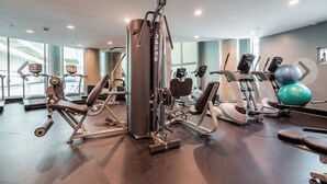 A gym with various exercise equipment, including a leg press machine, a bench press, and a rowing machine.