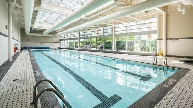 An indoor swimming pool with clear lanes, a tiled deck, and large windows allowing natural light.