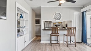 A compact kitchen with a central island, wooden chairs, and a ceiling fan.