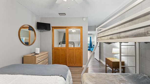 A bedroom with a bed, a dresser, a mirror, a wardrobe, and a bunk bed.