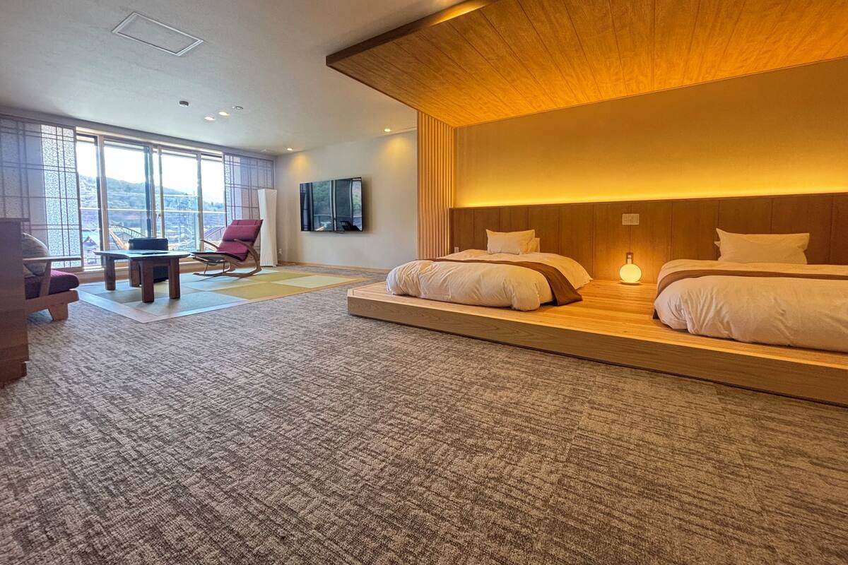 A hotel room with a large bed, a desk, a chair, and a TV.