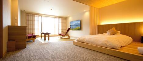 A modern bedroom with a large bed, a rocking chair, and a view of a mountain through a window.
