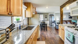 A kitchen with wooden cabinets, granite countertops, a built-in oven, and a dining area with a chair and table.