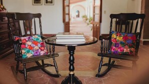 Une pièce avec deux fauteuils à bascule, une petite table avec des livres et un sol carrelé.