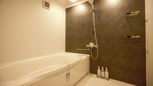 A modern bathroom with a bathtub, a shower, and a vanity with toiletries. - No.12 Kashima Fan Zone (Kashima)