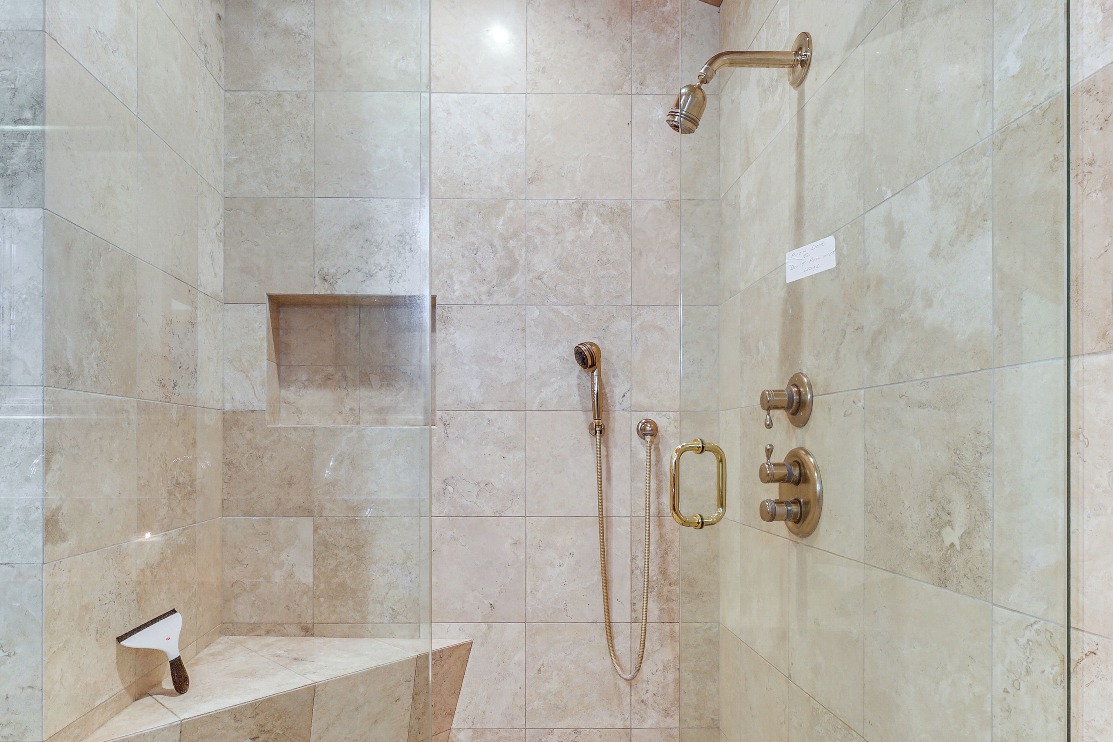 Ein Badezimmer mit Dusche, einer Sitzbank und einem Handtuchhalter.