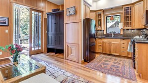 A spacious kitchen with wooden cabinets, a large refrigerator, and a dining area with a glass table and vase. - 11 Mi to Downtown Napa: Wine Country Cottage (Napa)
