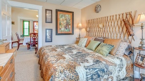 A bedroom with a large bed, a wooden headboard, a dining table with chairs, and a door with a green frame. - < 1 Mi to Old Town Lansing: Home w/ Furnished Deck (Lansing)