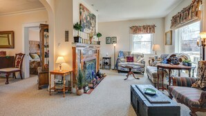 A cozy living room with a fireplace, comfortable seating, and a view of the outdoors. - < 1 Mi to Old Town Lansing: Home w/ Furnished Deck (Lansing)