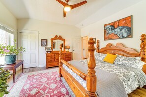 A bedroom with a wooden four-poster bed, a large mirror, a painting on the wall, and a potted plant by the window. - Hot Tub, Deck & Fire Pit: Chic Louisville Home! (Louisville)