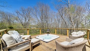 Eine Holzterrasse mit Korbmöbeln, einem Whirlpool und Blick auf kahl stehende Bäume.