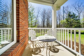 A patio with a brick wall, white railing, and a table with two chairs. - Hot Tub, Deck & Fire Pit: Chic Louisville Home! (Louisville)