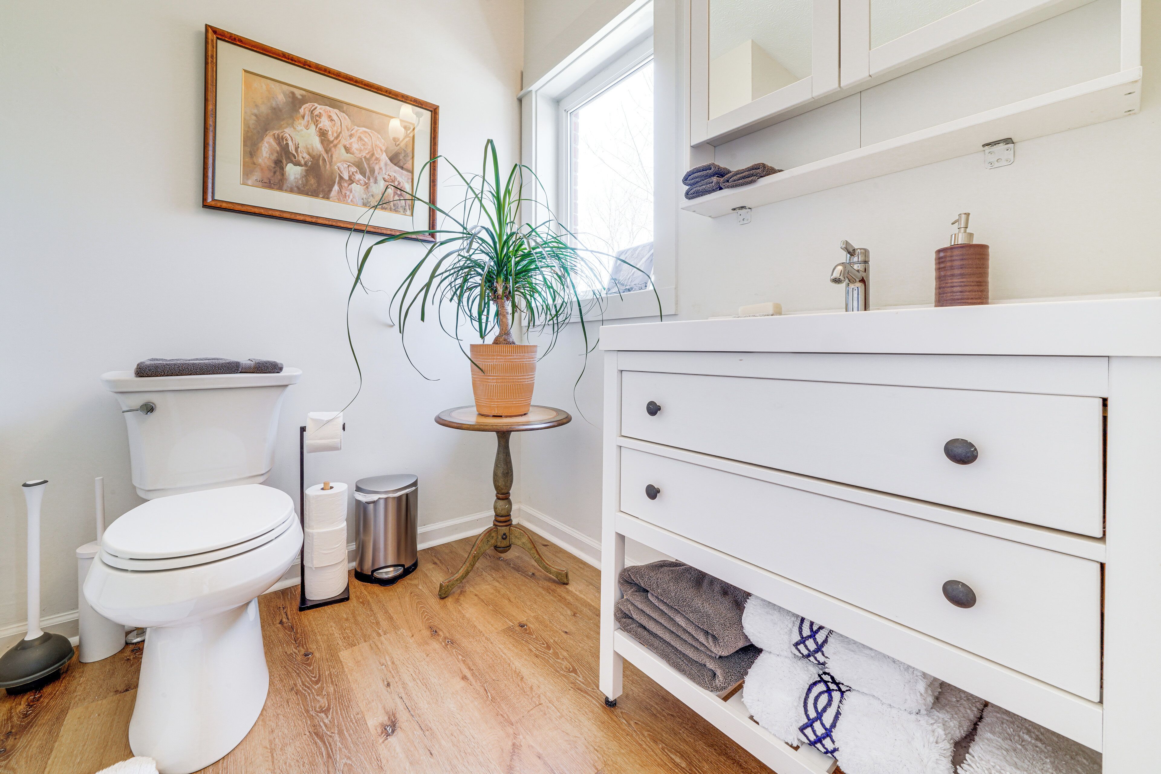 Et moderne badeværelse med toilet, vask og en potteplante.