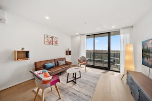 Relax in this inviting living room with a leather sofa, coffee table, and colorful chair, offering a view of the surrounding mountains.