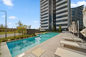 Relax by the pool surrounded by a deck with lounge chairs and umbrellas.