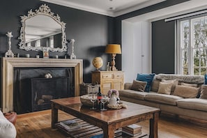 A living room with a fireplace, sofa, coffee table, and a large window.