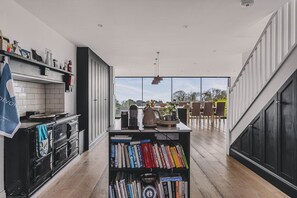 A modern kitchen with a central island, bookshelves, and a view to an outdoor dining area.