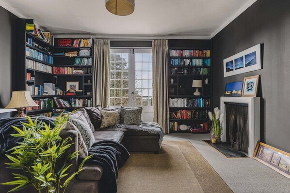 Una sala de estar con un sofá, una chimenea y una estantería llena de libros.