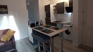 Un espacio habitable compacto con kitchenette, comedor y sofá.