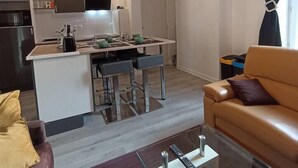 Cocina moderna con una isla central, zona de comedor con sofá y sala de estar con diván.