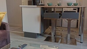 Una cocina moderna con una isla central, electrodomésticos integrados y un comedor con mesa de vidrio.