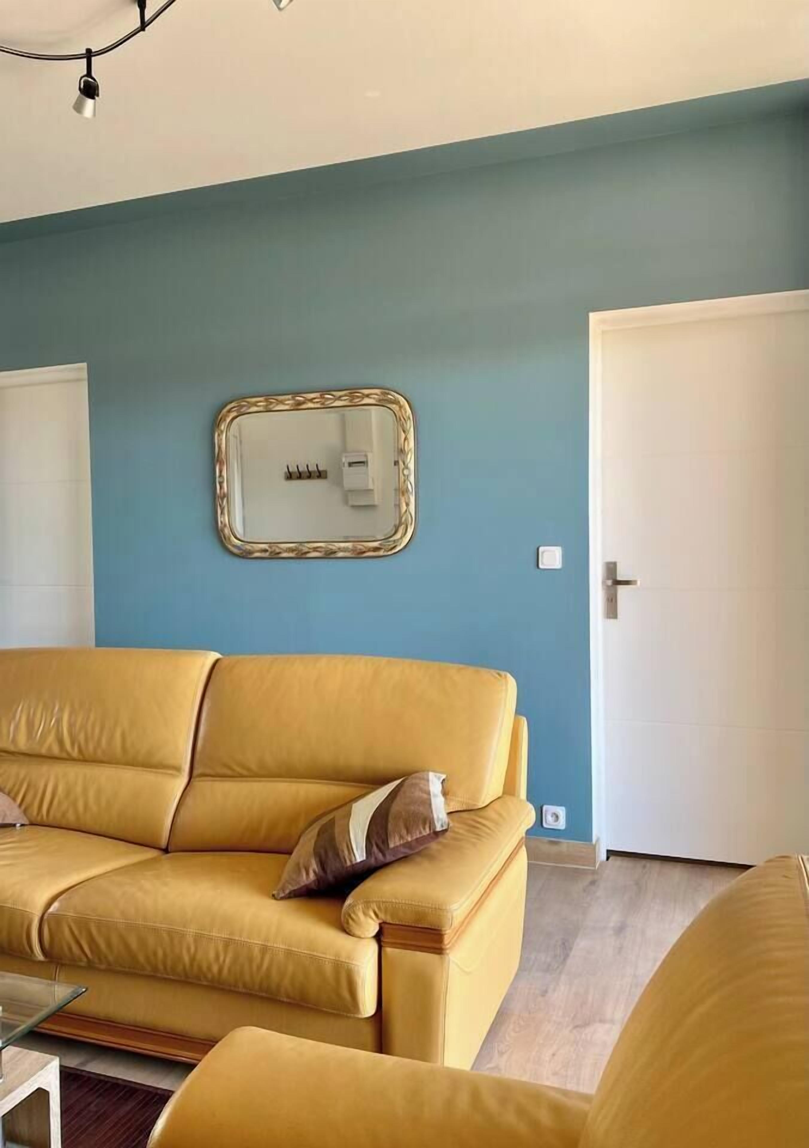 A room with a yellow sofa, a small table, and a wall-mounted light fixture.