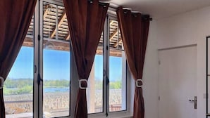 Une chambre avec un grand lit, une fenêtre avec des rideaux et une vue sur un vignoble.
