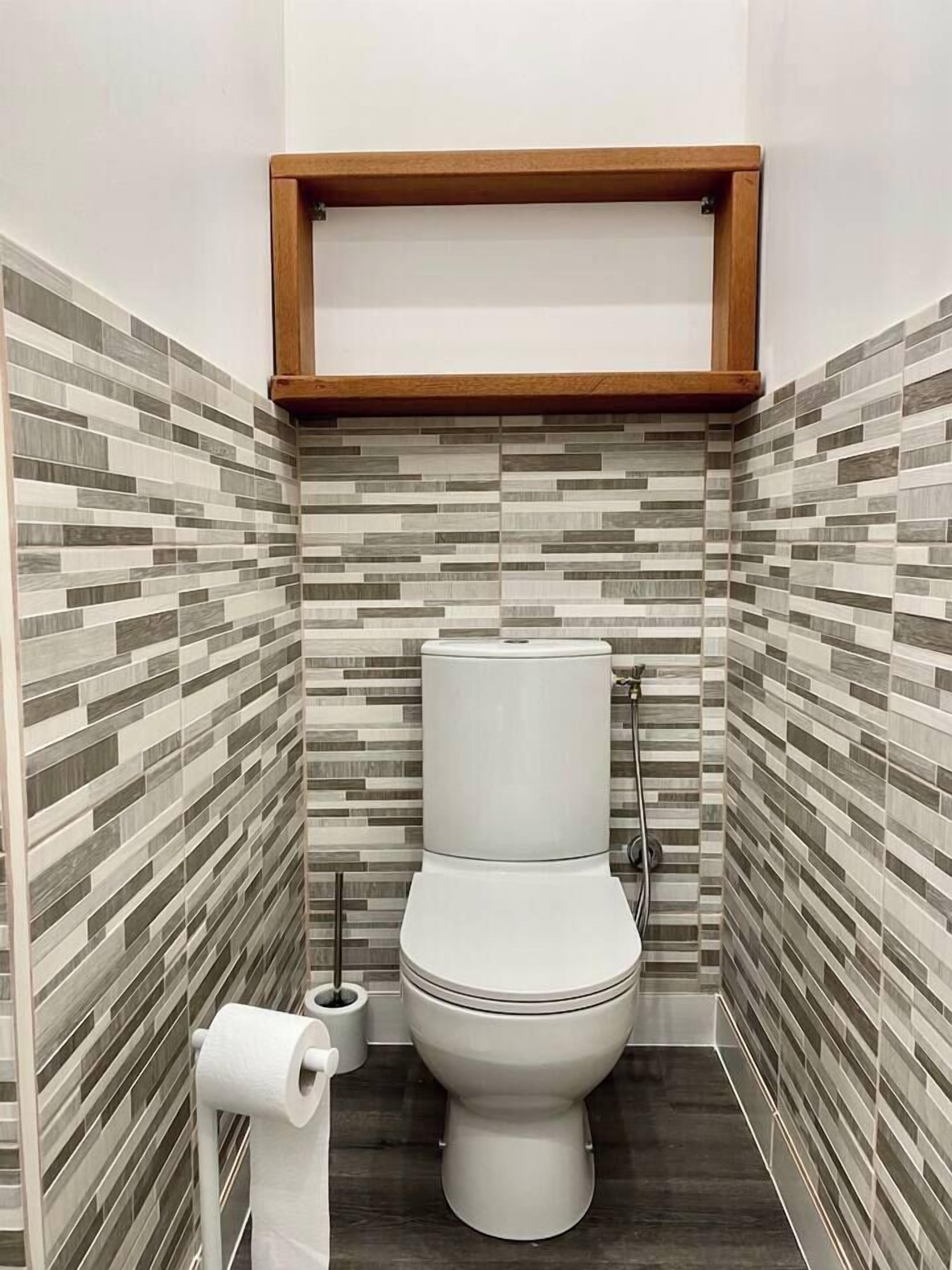 Ein modernes Badezimmer mit Toilette, Toilettenpapierhalter und Dusche.
