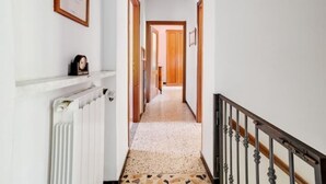 A hallway with a radiator, a clock, and a wooden door at the end.