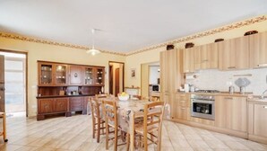 A spacious kitchen with wooden cabinets, a dining table with chairs, and a large window.