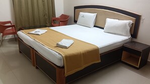 Ein Hotelzimmer mit einem Bett, einem Nachttisch, einem Sessel und einem Vorhang.