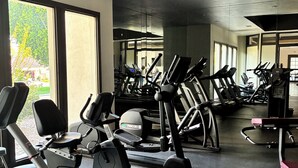 Un gimnasio con diversas máquinas de cardio, amplios ventanales y un diseño moderno.