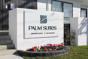 Señal para el Palm Suites Boutique Hotel, con logotipo, nombre y dirección.