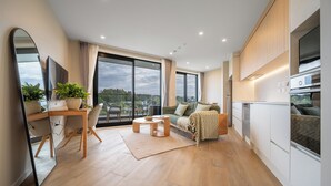 Um apartamento moderno com área de refeições, sofá, cozinha e janelas amplas com vista para a cidade.