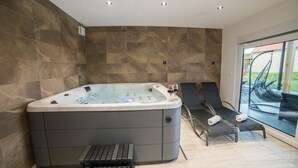 A modern bathroom with a large bathtub, a small table, and two lounge chairs. - Villa Old Hills by Villas Guide (Ljubešcica)
