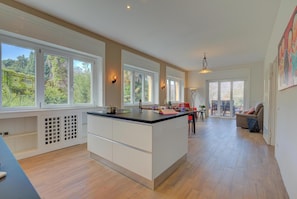 Enjoy meals in a spacious kitchen with a central island, large windows, and a dining area.